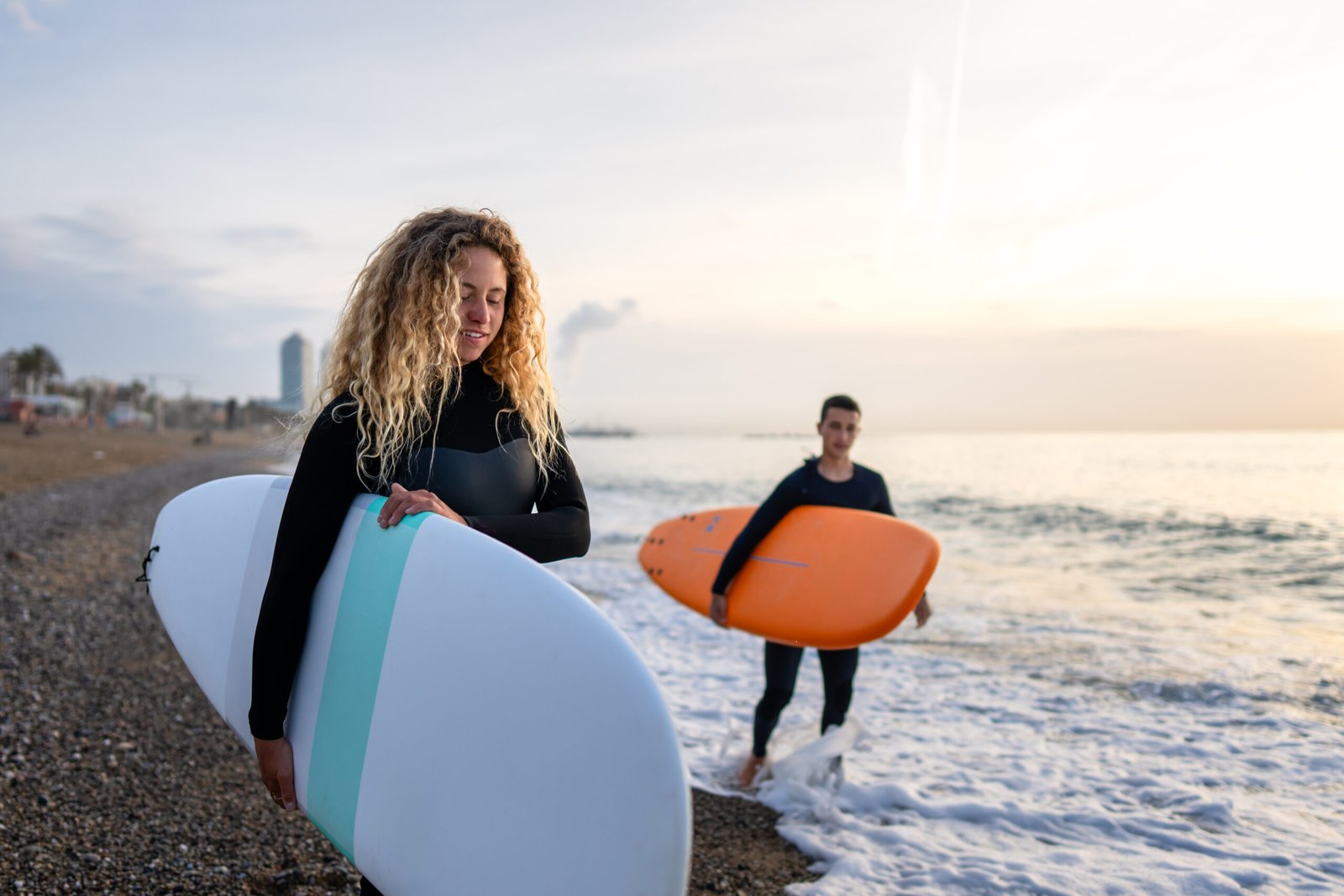 Two happy young surfers with surfboard prepares to hit the waves at sunset. Sports active lifestyle vacation concept
